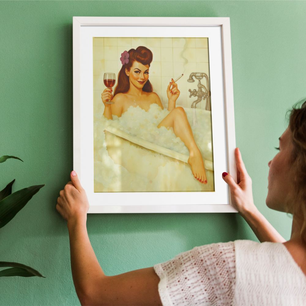 Person holding a framed artwork of a woman in a bathtub with a glass of wine and a cigarette.