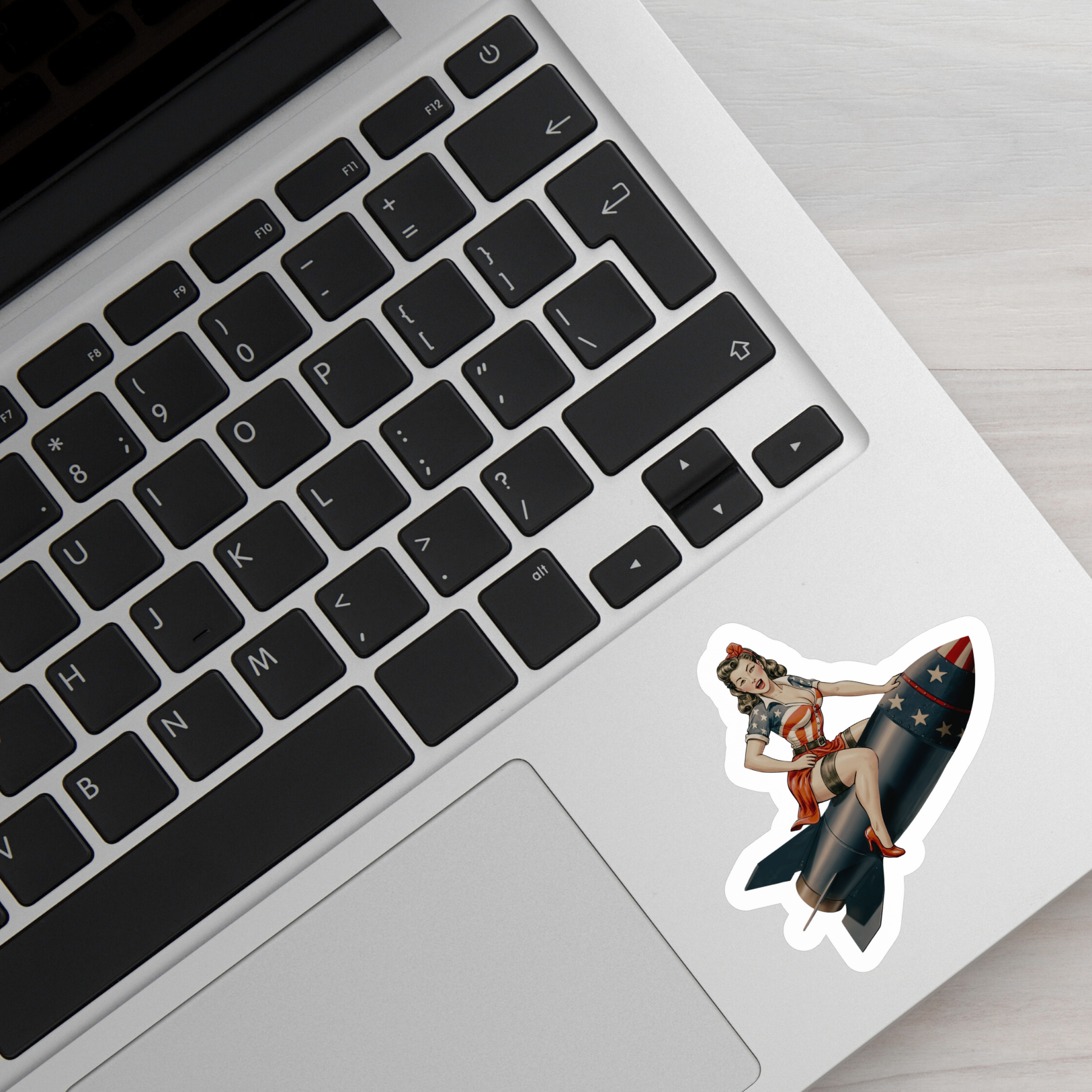 Laptop with a sticker of a woman on a rocket on the palm rest area